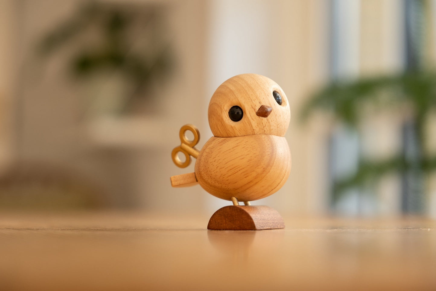 
                  
                    Nattergalen figuren i hjemmet. Står på spisebord som dekoration, med planter i baggrunden og gyldent sollys i rummet. 
                  
                